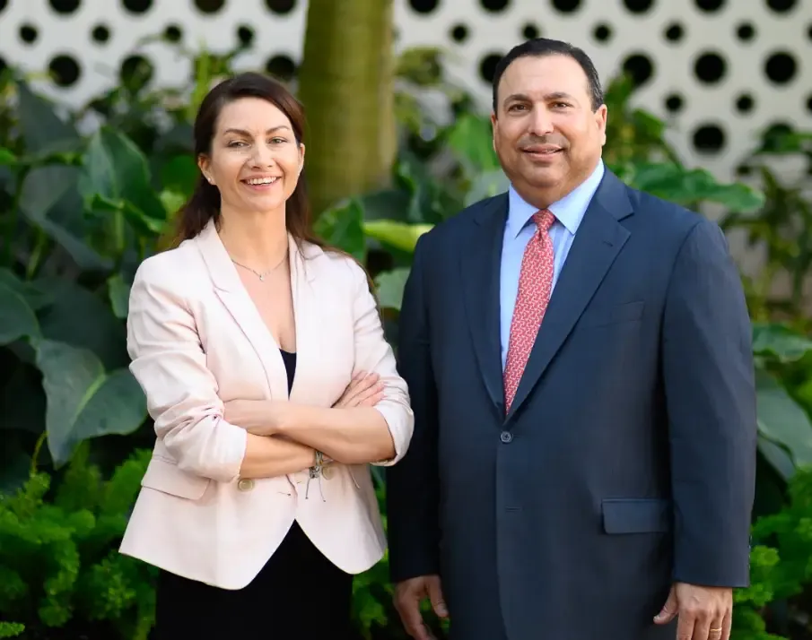A woman and a man in business attire pose for a professional photo