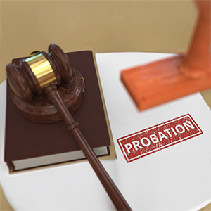 A wooden gavel on a legal book and a document stamped with the word PROBATION in red.